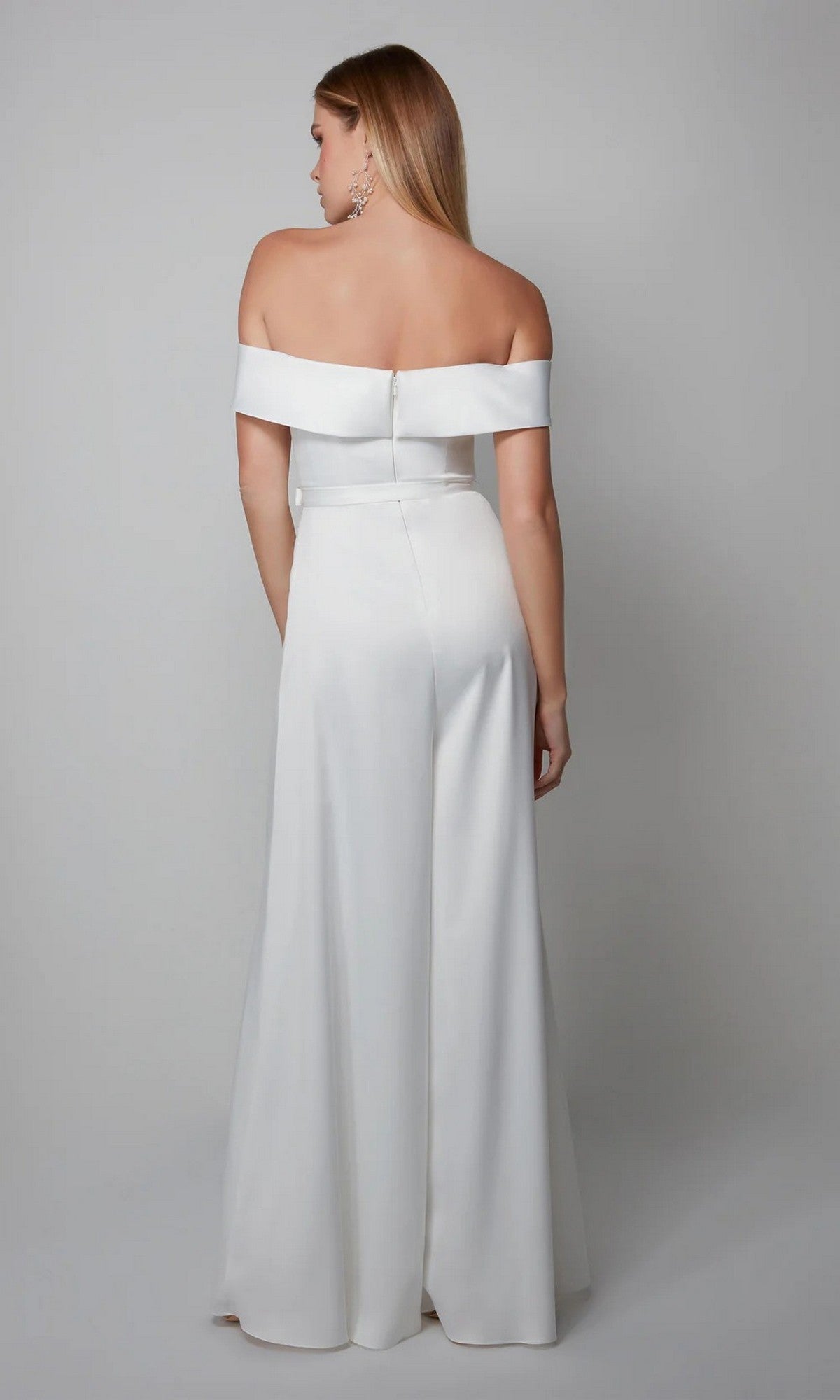A woman models the Long Formal Jumpsuit: Alyce 70012, facing away from the camera in a white off-the-shoulder style against a plain gray background.
